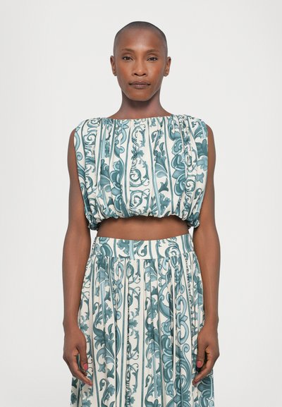 Ensemble deux pièces composé d'un top court plissé et d'une longue jupe. Le tissu présente un motif floral turquoise et blanc avec des lignes verticales.
