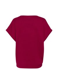 Top magenta à manches courtes avec une coupe décontractée, encolure arrondie et texture lisse. Aucune motif ni détail en métal visible.
