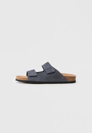 Sandalia de ante gris oscuro con dos correas ajustables, plantilla de corcho y suela de goma negra texturizada. Presenta un diseño minimalista.