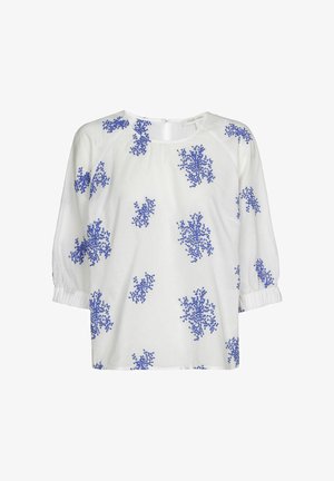 Blouse blanche avec des motifs floraux bleus, encolure ronde et manches trois-quarts avec poignets élastiques. Comprend un détail d'ouverture au dos.