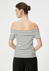 Off-shoulder top i hvid med sorte striber, korte ærmer, ribbet tekstur, tætsiddende design og en sømløs rygpanelet.