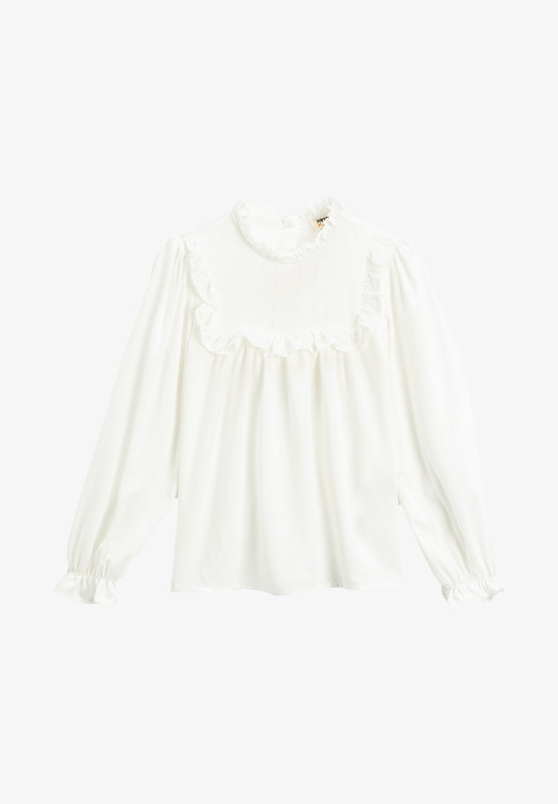Blouse blanche à manches longues avec col montant à volants, empiècement à volants sur la poitrine et poignets élastiques à volants.