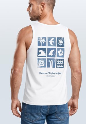 Man wearing white tank top with blue tropical icons and text "take me to paradise" on the back, paired with blue denim jeans.