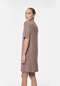 Robe brune courte à manches courtes et coupe ample, avec un col rond et une texture lisse sur un fond clair.