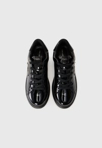 Adidași din piele patentată neagră, cu vârf rotund, șireturi plate și logo pe lateral. Textură netedă și design de profil jos.