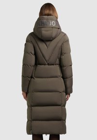 Lang, olivengrøn puffjakke med hætte. Har horisontale quiltede sektioner, et logo på ryggen og sidelommer med lynlås.