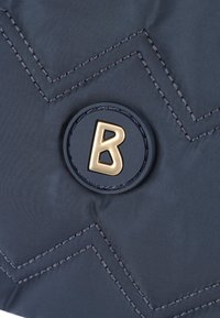 Borsa in nylon trapuntato blu navy con un logo rotondo prominente in nero e oro raffigurante la lettera "B", accentuata da cuciture a chevron.