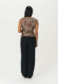 Haut sans manches à motif floral marron avec une texture froncée, associé à un pantalon large taille haute noir.
