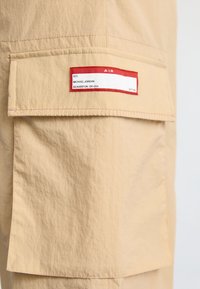 Poche en tissu beige avec une étiquette bordée de rouge portant l'inscription « #23 Michael Jordan Beaverton, OR USA » et le mot « AIR » en haut.