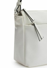 Witte leren handtas met een textuur oppervlak, voorzien van twee met rits afgesloten vakken en een elegante handgreep met zwarte accenten.