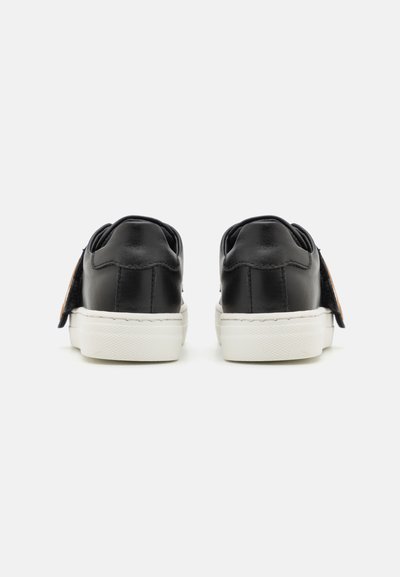 Sneaker in pelle nera con suole in gomma bianche, dotate di un tallone testurizzato e di un dettaglio laterale. Design pulito e minimalista.