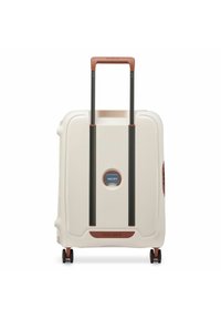 Valigia rigida di colore bianco sporco con superficie texture. Presenta una maniglia marrone e un carrello retrattile nero, montato su quattro ruote.