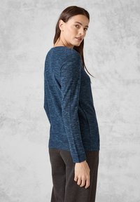 Marinblå långärmad topp med en strukturerad, ribbad design. Har en rundad halsringning och en avslappnad passform, visad sedd bakifrån.