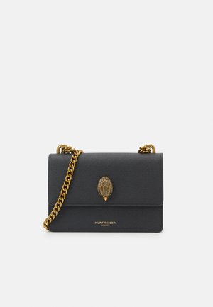 Sac à bandoulière en cuir noir avec bandoulière chaîne dorée et emblème doré, présentant le logo Kurt Geiger London sur le rabat avant.