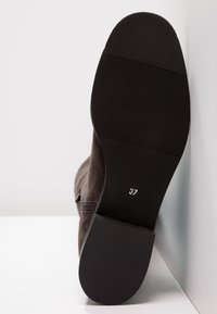 Braune Wildleder-Ankle Boots mit einer strukturierten schwarzen Gummisohle. Größe 37 auf der Unterseite markiert, mit einem seitlichen Reißverschluss zum Verschließen.