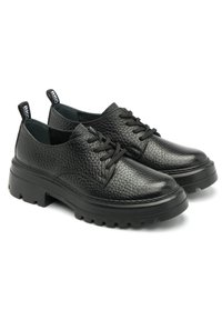 Chaussures en cuir noir avec une texture granuleuse, bout rond et semelle en caoutchouc épaisse. Présentent un design à lacets et une languette à l'arrière pour un enfilage facile.