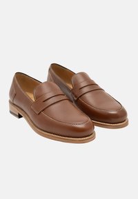 Braune Lederloafer mit texturierter Oberfläche, flacher Sohle und genähtem Akzent im oberen Bereich. Einfaches, zum Hineinschlüpfen geeignetes Design mit glatter Zehenpartie.