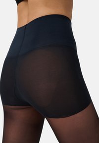 Hoch taillierte schwarze Leggings aus glattem, blickdichtem Material, das am Oberschenkel in ein durchsichtiges Gewebe übergeht, mit nahtlosem Design.