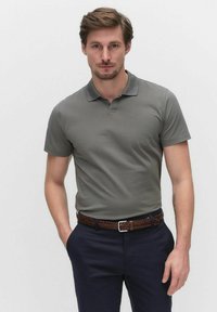 Kortärmad polo i grå bomull, med en klassisk krage och en plattstickad design, kombinerad med marinblå byxor och ett flätat brunt bälte.