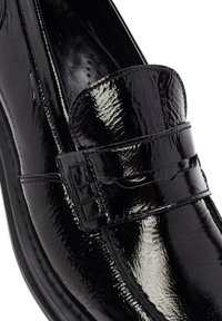 Scarpa slip-on in vernice nera con punta arrotondata, caratterizzata da una fascia testurizzata sulla tomaia e dettagli di cucitura in contrasto.