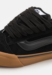 Svart mockaskor med svarta snörningar och läderdetaljer. Har en gummigummisula, sömmande detaljer och perforeringar på sidan.