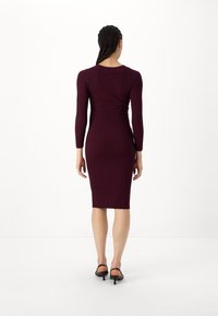 Abito midi a costine bordeaux con maniche lunghe. La vestibilità bodycon esalta la silhouette. Presenta un collo rotondo e una texture liscia.