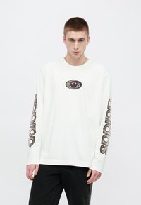 Fehér hosszú ujjú ing, színes emblémával a mellkason, és fekete "adidas" felirattal a bal ujjon. Pamut anyagból.