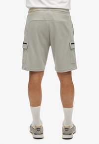 Lichtgrijze cargoshorts met elastische tailleband, zijzakken en zwarte accenten. Gemaakt van zachte, gestructureerde stof. Tot halverwege de dij.
