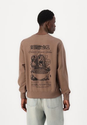 Sweatshirt en coton marron avec un imprimé graphique d'un bol de ramen et un design de lion au dos. Poignets et ourlet côtelés.