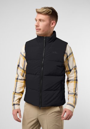 Gilet imbottito nero con colletto alto, zip frontale, due tasche laterali, indossato sopra una camicia a quadri multicolori con accenti gialli. Texture liscia.