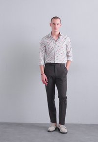 White button-up shirt with a floral pattern, paired with dark trousers and beige shoes. Smooth fabric, tailored fit, and modern design.