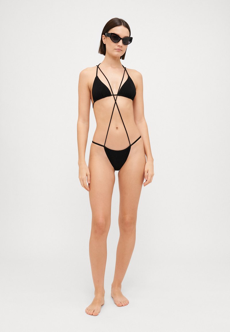Bikini nero con coppe triangolari, spalline sottili e slip a vita bassa. Il design con cordini regolabili offre un aspetto minimalista.