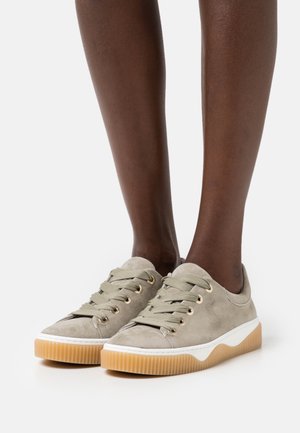 Sneakers in suede verde oliva con suola in gomma nocciola, punta tonda e design con lacci, caratterizzati da occhielli dorati e una suola intermedia bianca in contrasto.