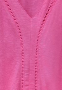 Roze V-hals top met een textuurpaneel met verticale, verlengde steken, gemaakt van een lichte, zachte stof.