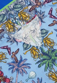 Lichtblauwe stof met een bloemen- en vlinderpatroon. Opmerkelijke details zijn gele bloemen, groene bladeren en een label met de tekst "CODELLO."