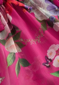 Cvjetna tkanina s živopisnom ružičastom pozadinom ukrašenom raznim uzorcima cvijeća i zelenim lišćem, naglašena razigranim leptirovima.