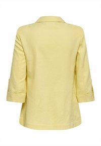 Veste jaune clair à manches longues avec un col et des manches trois quarts, vue de dos sur fond blanc.