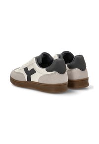 Zapatillas de cuero y gamuza en crema, gris y negro, con una gruesa suela de goma marrón y un logotipo prominente en el talón.