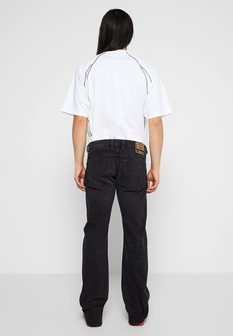Weißes kurzärmeliges Hemd mit schwarzem Stich versehen, kombiniert mit schwarzen Jeans mit Logo-Patch und geradem Schnitt. Textilstruktur, lässiges Design.