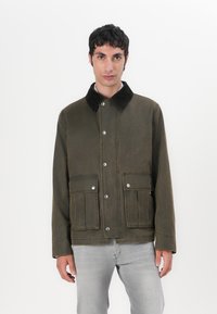 Olive green jacket with a corduroy collar, snap buttons, and two front pockets; made from sturdy fabric with visible stitching details.