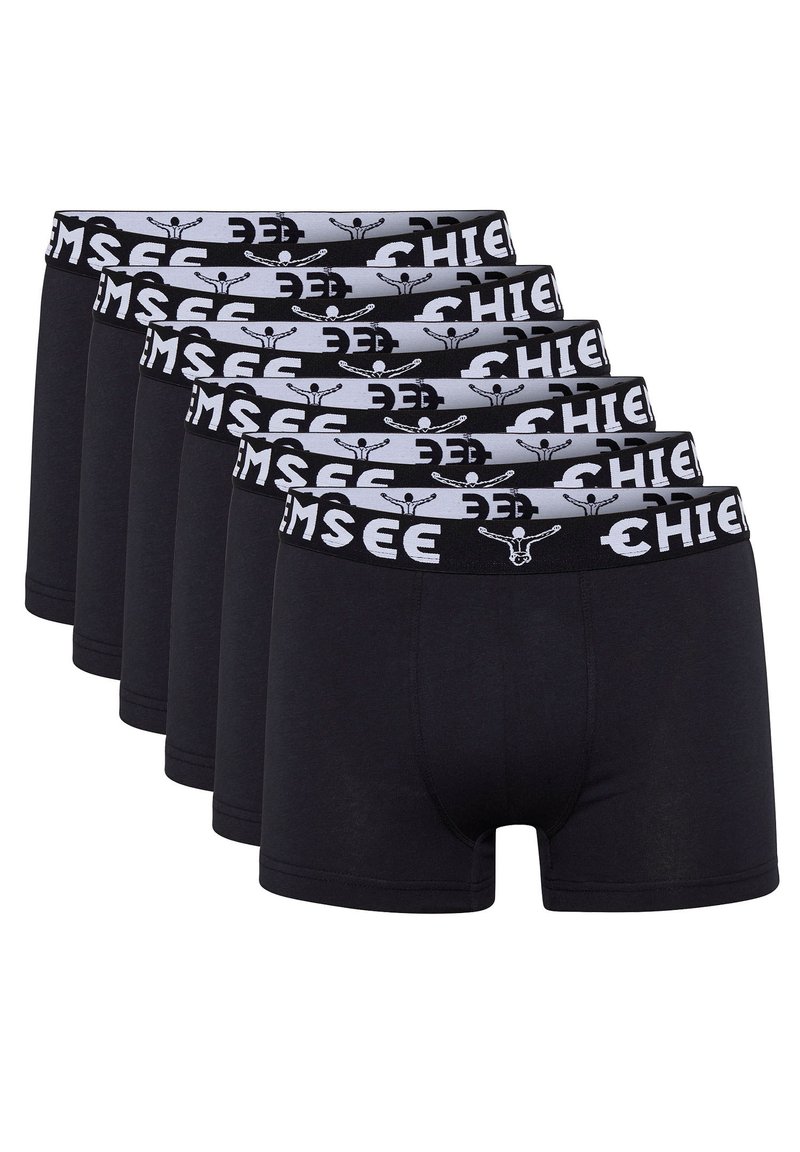 Schwarze Baumwollboxershorts, die in einer Reihe präsentiert werden, mit einem grauen Bund und einem Muster aus schwarzem Text und Logo. Sechs Paar sind sichtbar.