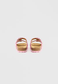 Ružové sandále s korkovou podrážkou, dvoma nastaviteľnými remienkami a textúrovanou podrážkou. Vrchný materiál pôsobí mäkko a ako tkanina.