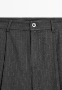 Gray pinstriped pants with pleats, featuring a button closure and slanted pockets. The fabric has a textured finish and tailored design.