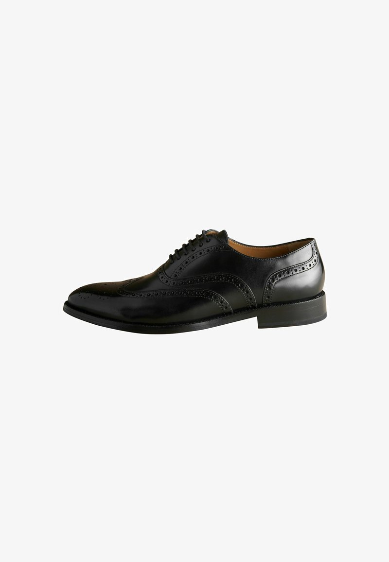 Musta nahkakenkä klassisella brogue-muotoilulla, jossa on rei'itettyjä yksityiskohtia, pyöreä varvas ja matala, tukeva korko.