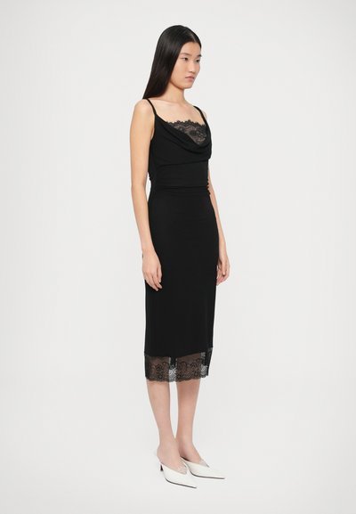 Čierne šaty s čipkovanou lemovkou na okraji a detailom čipky pozdĺž výstrihu. Majú nastaviteľné ramienka a priliehavý strih.