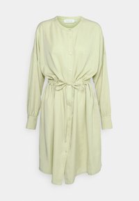 Vestido em verde claro com botões, com cordão na cintura, mangas longas e decote redondo. Feito de um tecido suave com um ajuste descontraído.