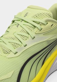 Απαλό πράσινο αθλητικό παπούτσι με πλέγμα στο πάνω μέρος, κορδόνια στο ίδιο χρώμα, μαύρες και γκρι πλαϊνές ρίγες και κίτρινη επικάλυψη στην σόλα.