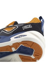 Baskets de sport avec un design bleu marine, noir et orange. Présentent un dessus texturé, une semelle intermédiaire blanche et une semelle extérieure en caoutchouc avec des accents orange.