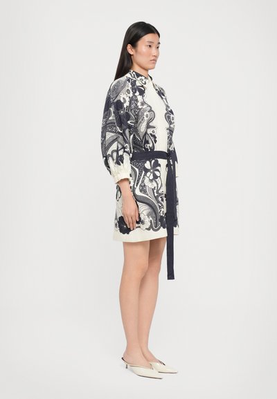 Rochie cu mânecă scurtă, cu model paisley în crem și bleumarin, cu talie ajustată și centură asortată. Material neted, de lungime medie până la genunchi, purtată cu încălțăminte ușoară.