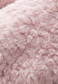 Blød, fluffy pink tekstureret stof med tætte, krøllede fibre, der skaber et hyggeligt, fyldigt udseende.